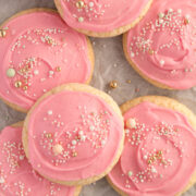 A tray of soft, pink frosted sugar cookies topped with colourful sprinkles – bakery-style cookies with thick, pillowy centres