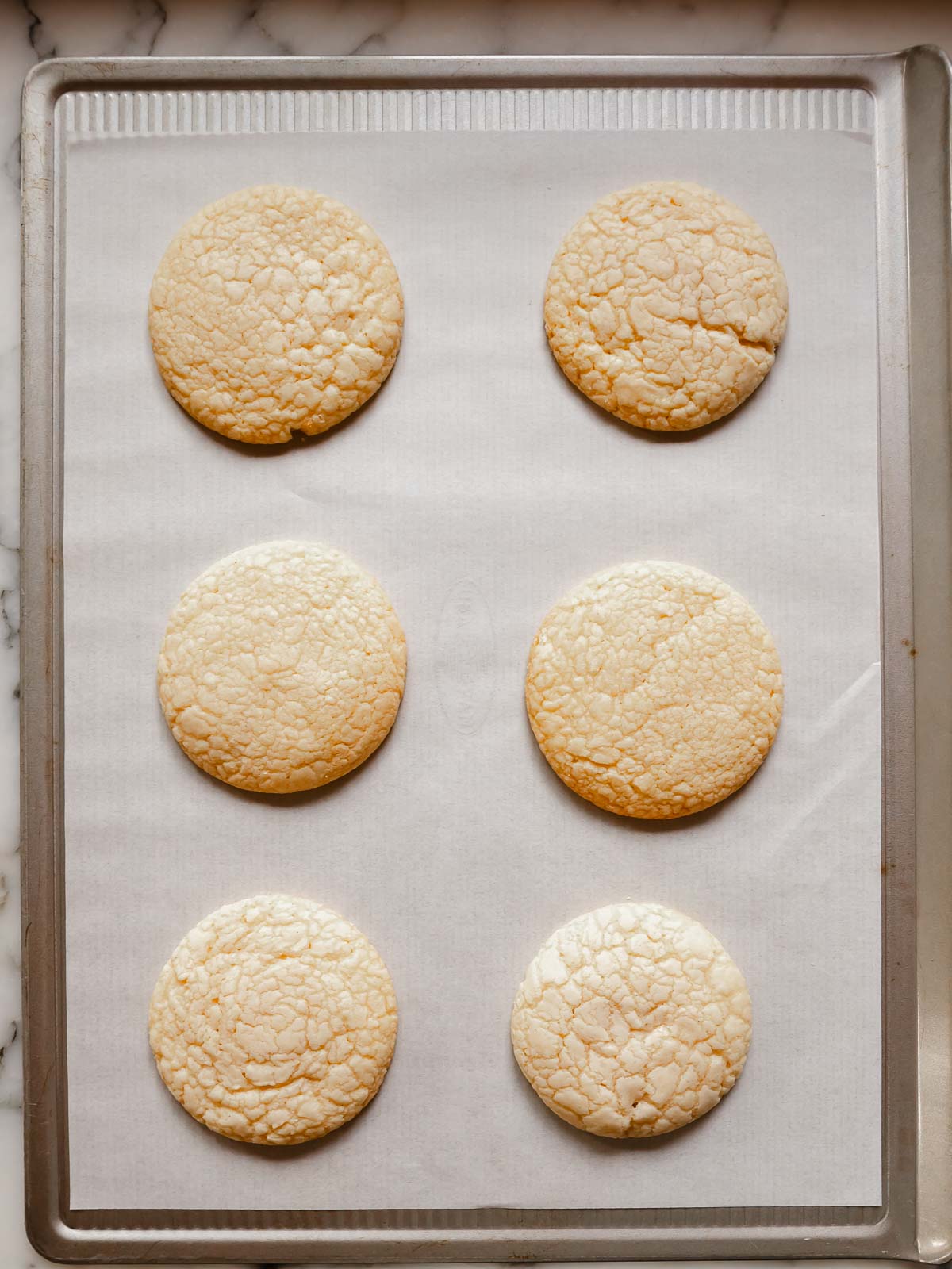 Freshly baked sugar cookies resting on tray—edges set but centres still soft and pale