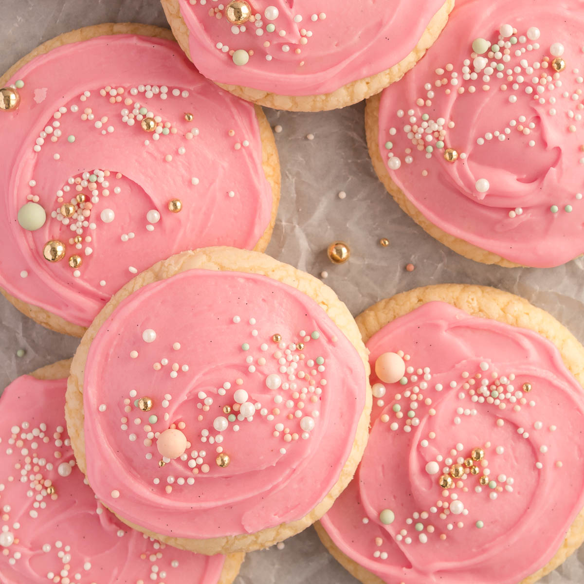 A tray of soft, pink frosted sugar cookies topped with colourful sprinkles – bakery-style cookies with thick, pillowy centres