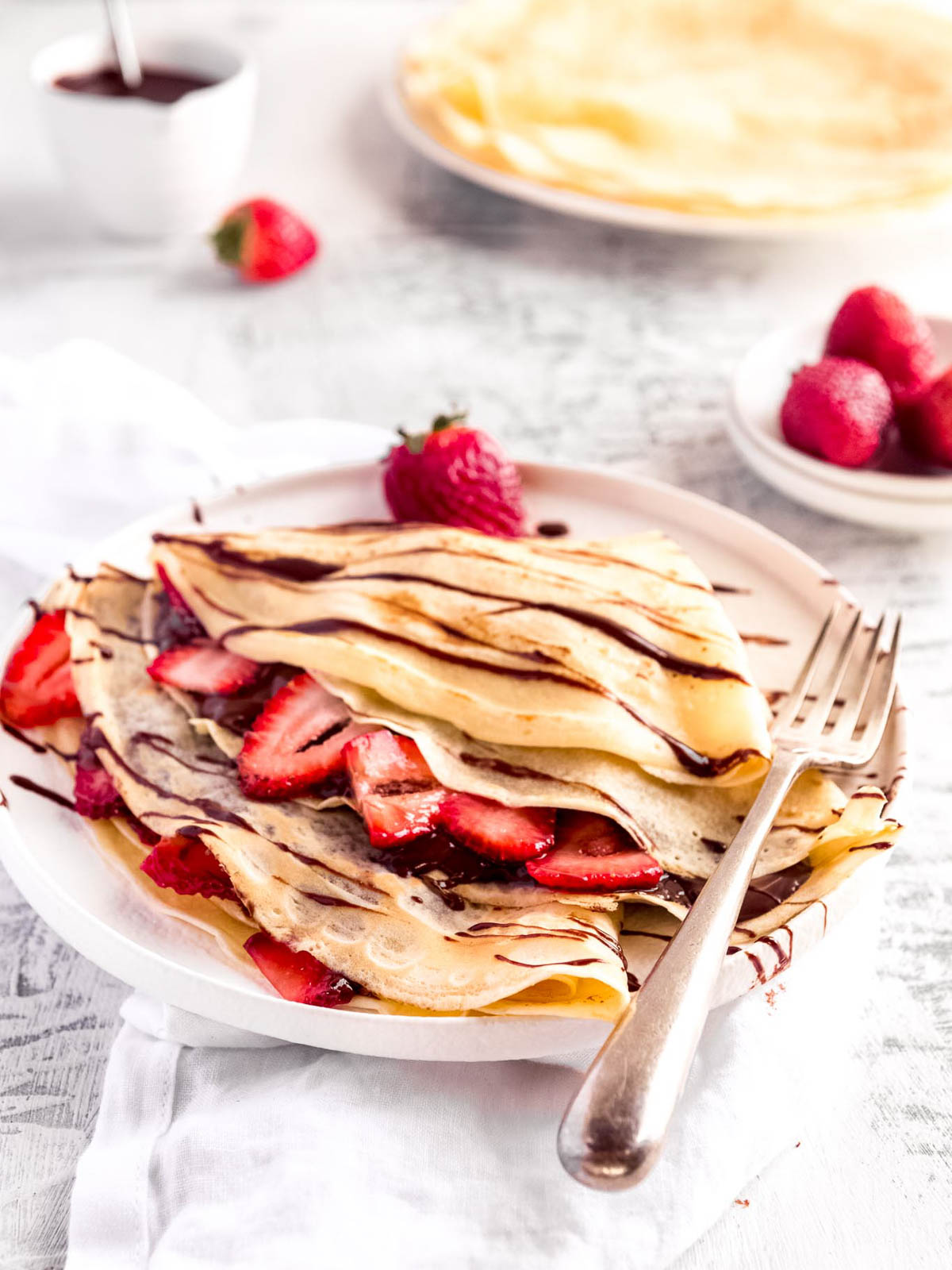 2 crepes filled with strawberries and nutella and drizzled with chocolate