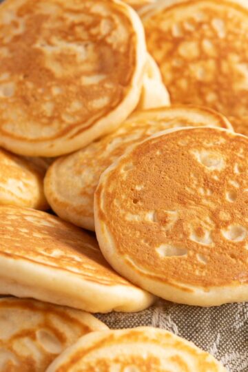 Mini pancakes or pikelets, resting on a linen tea towel to serve.
