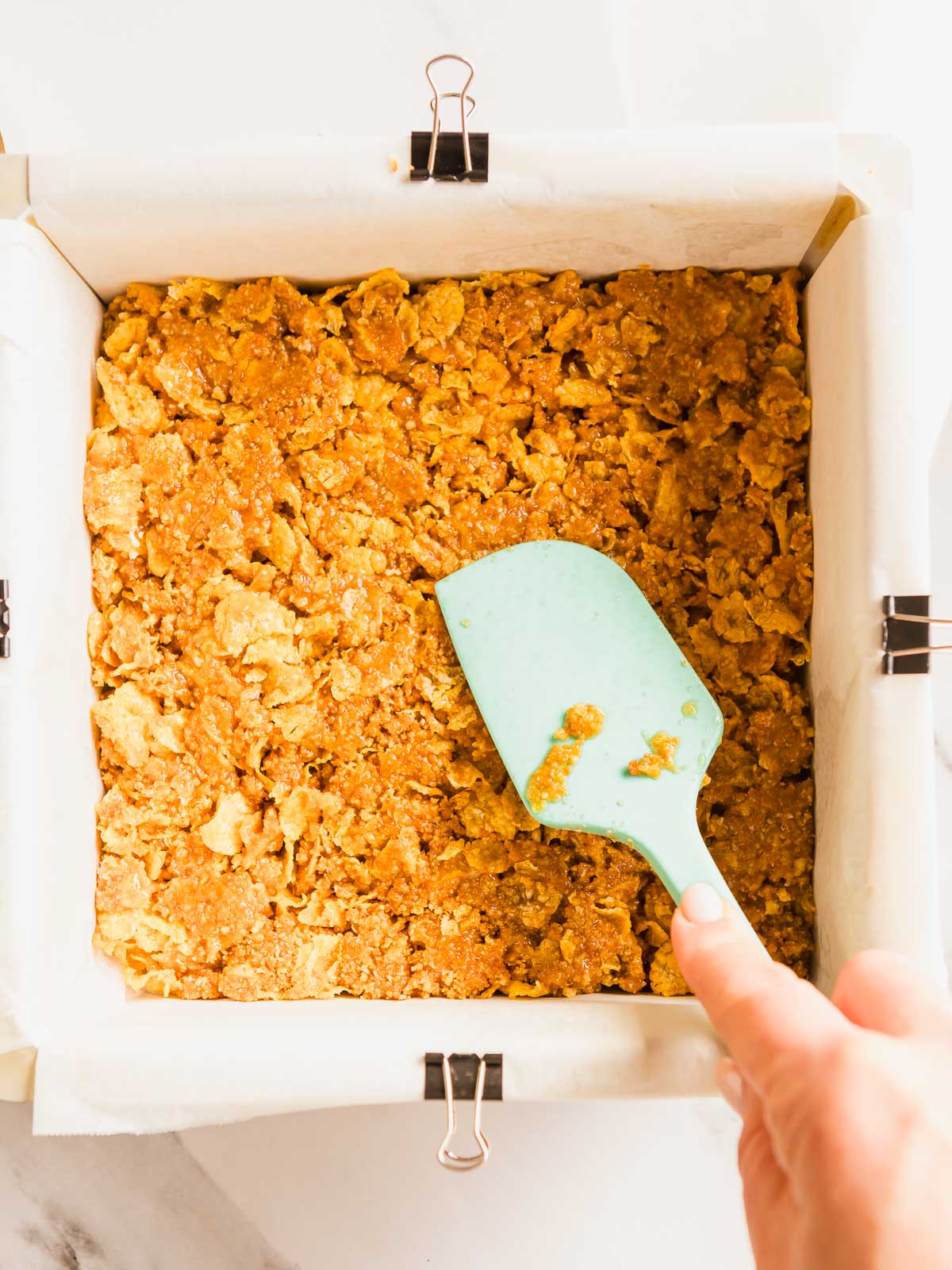 Pressing the honey joy mixture into a slice tin.