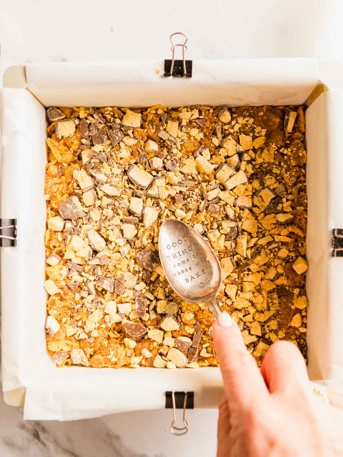 Pressing the honey joy mixture into a slice tin.