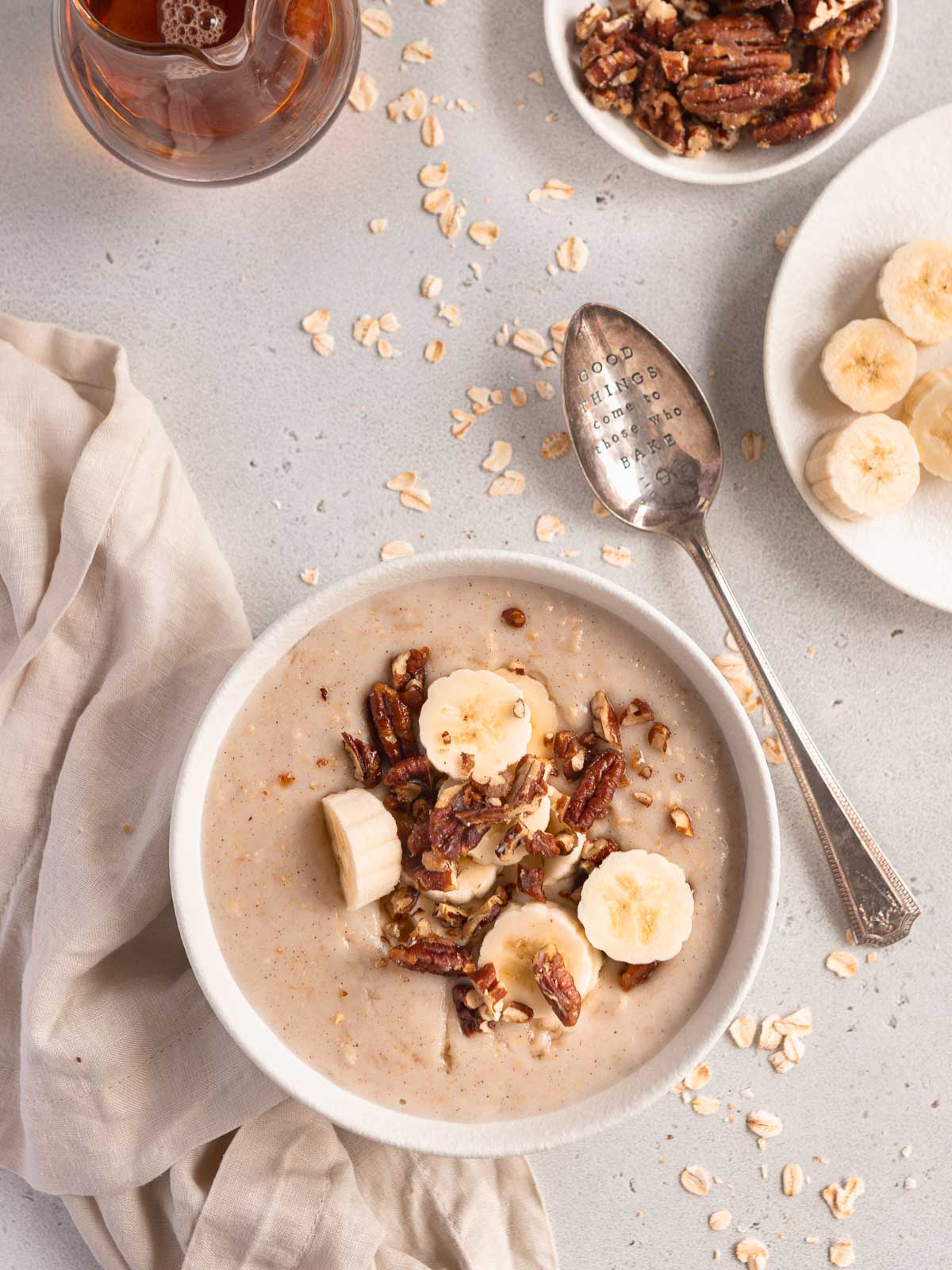 A bowl of creamy porridge, topped with candied nuts and banana.