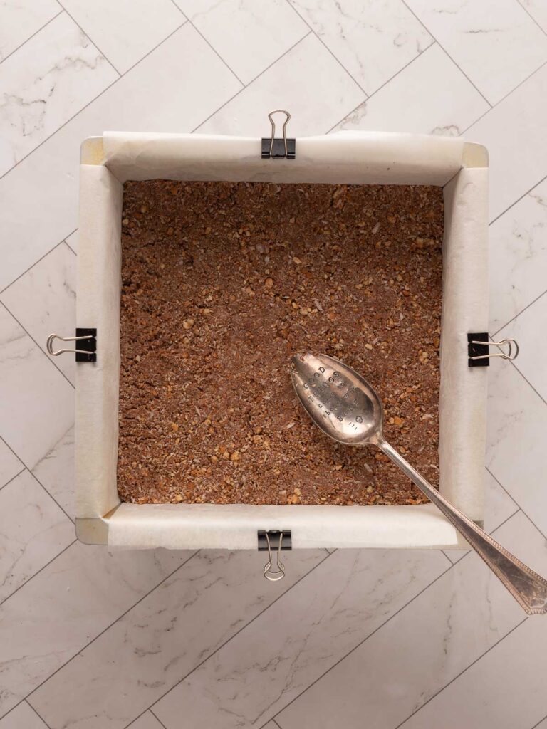 Pressing the base of the peppermint slice into a lined 20cm square tin.