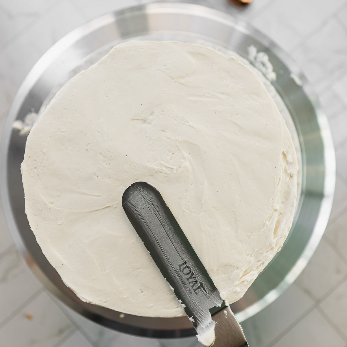 Smoothing off the top of a 3 layer vanilla cake, using an offset spatula.