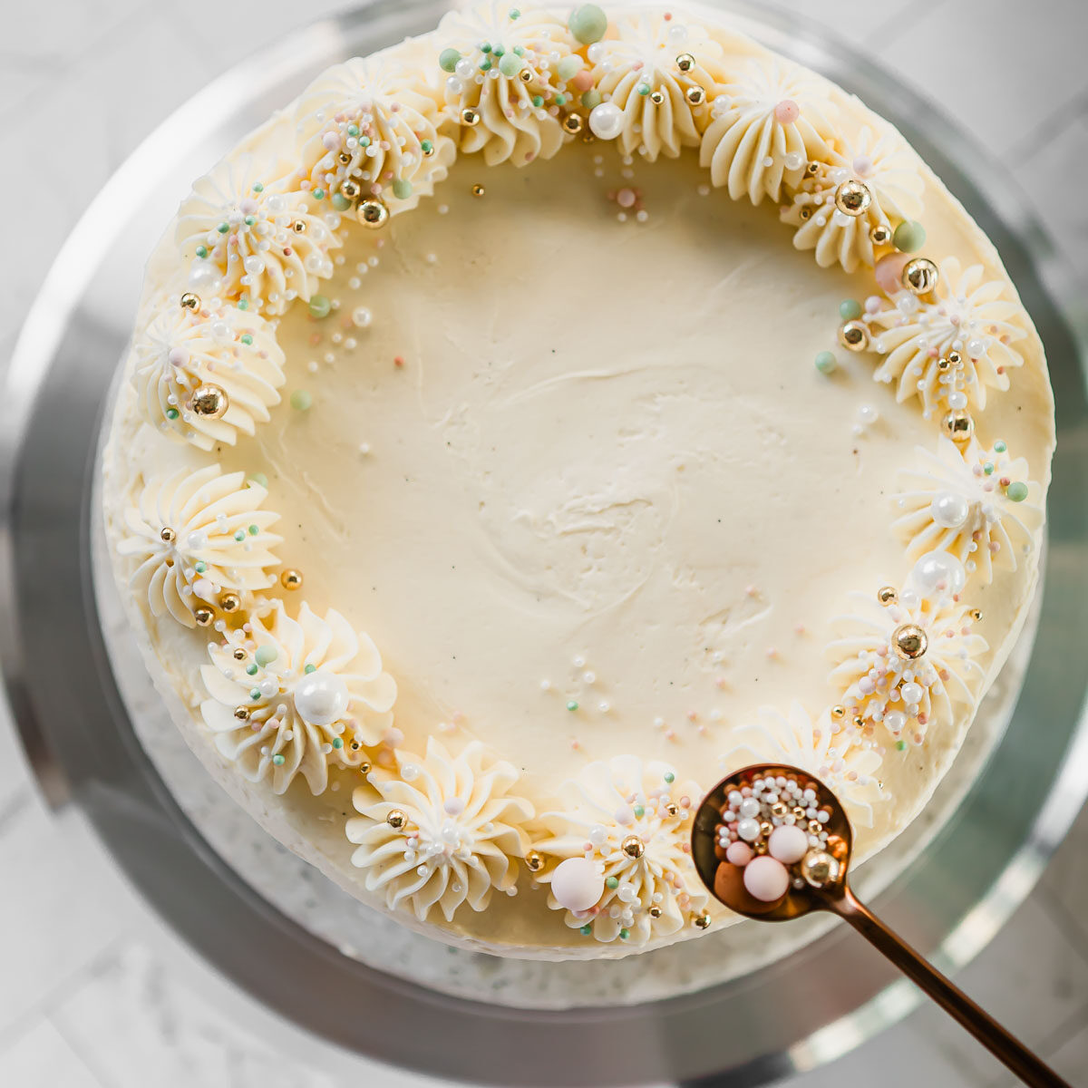 Finish off a 3 layer vanilla cake with piped frosting and coloured sprinkles.
