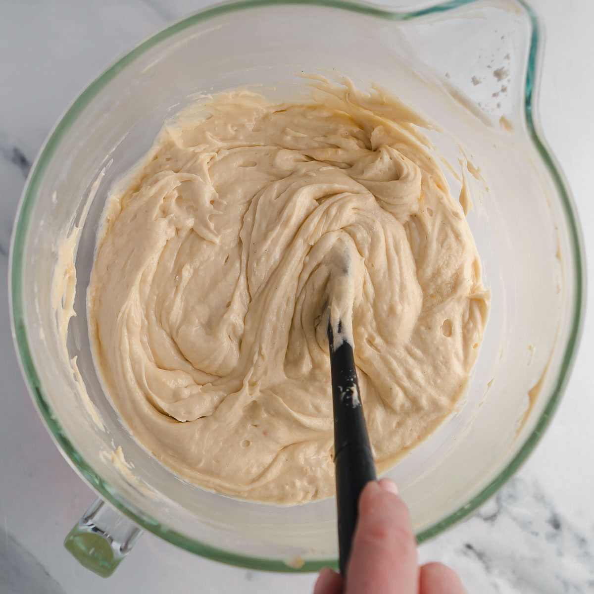 Mixing the dry ingredients into the wet ingredients -a step in how to make a 3 layer vanilla cake.