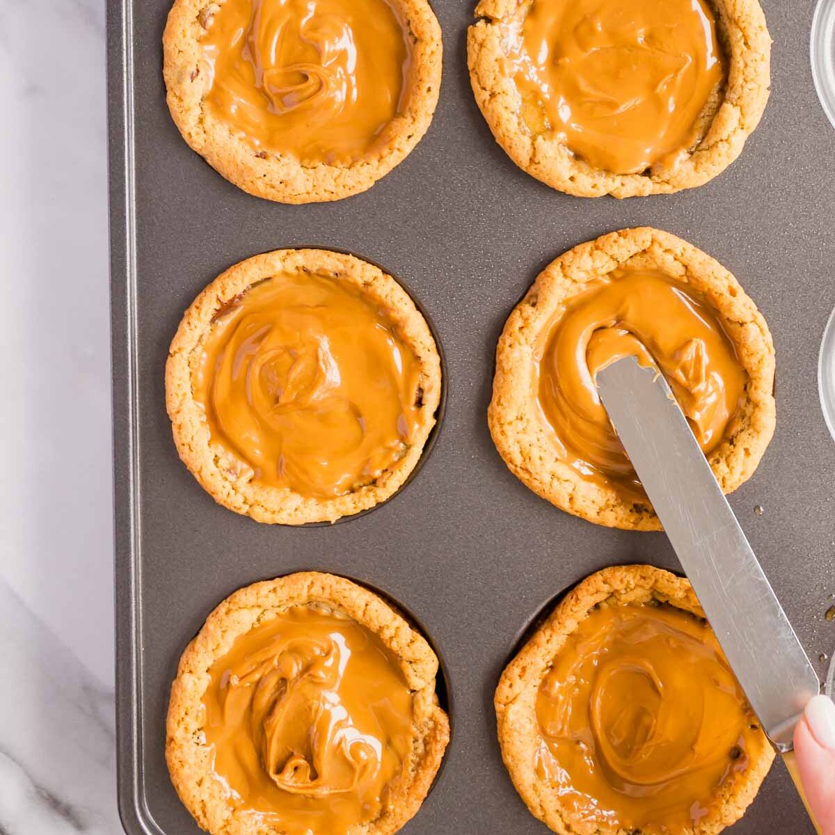Spreading biscoff spread into the baked cookies.