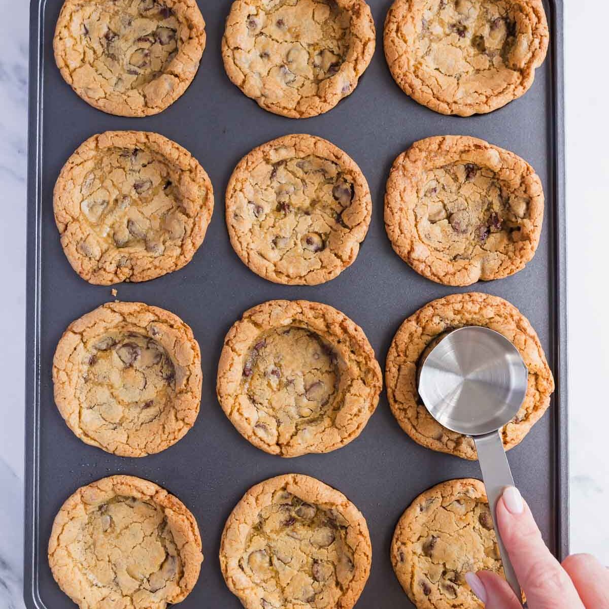 Pressing a cup into the baked cookies, to make a divot.