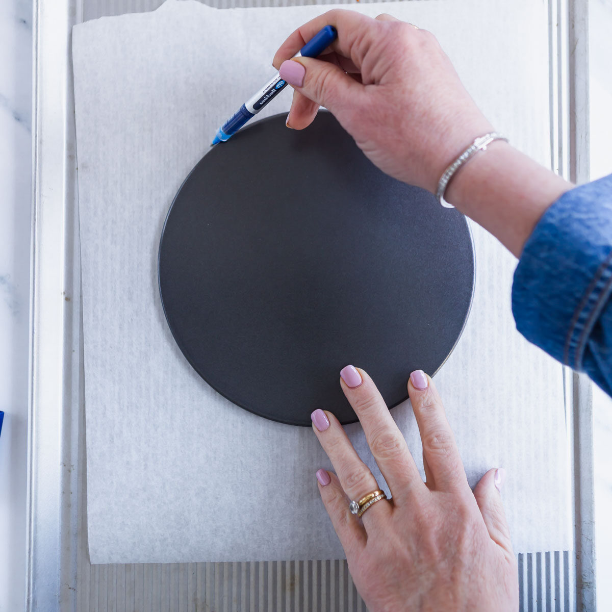 Baking tray lined with parchment paper and a drawn circle for pavlova base.