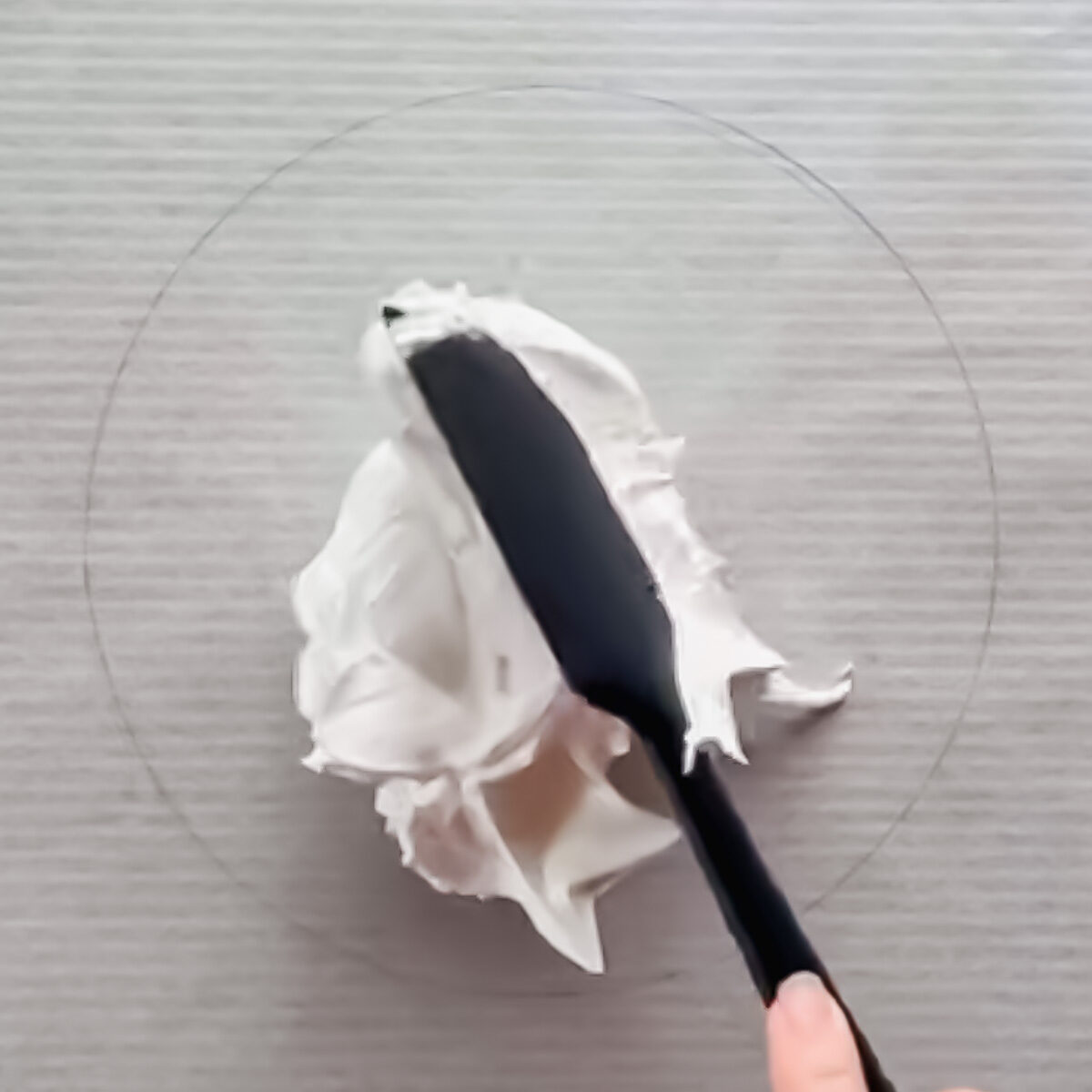 Baking tray lined with parchment paper and a drawn circle for pavlova base.