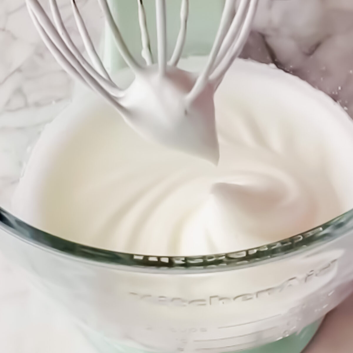 Egg whites being whipped in a mixing bowl until soft peaks form.