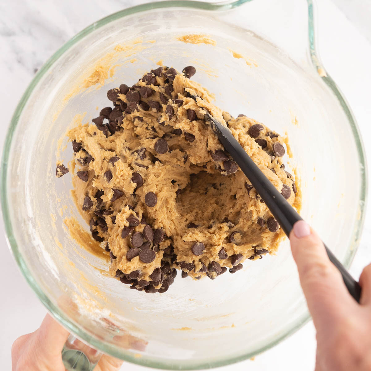 Mixing in chocolate chips by hand to make no chill chocolate chip cookies.