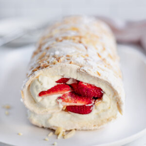 A fluffy pavlova roll, filled with cream, strawberries and crunchy slivered almonds.