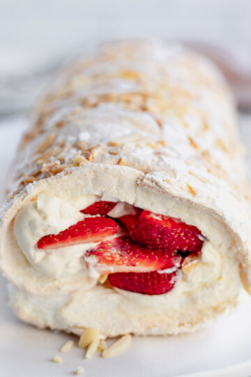 A fluffy pavlova roll, filled with cream, strawberries and crunchy slivered almonds.
