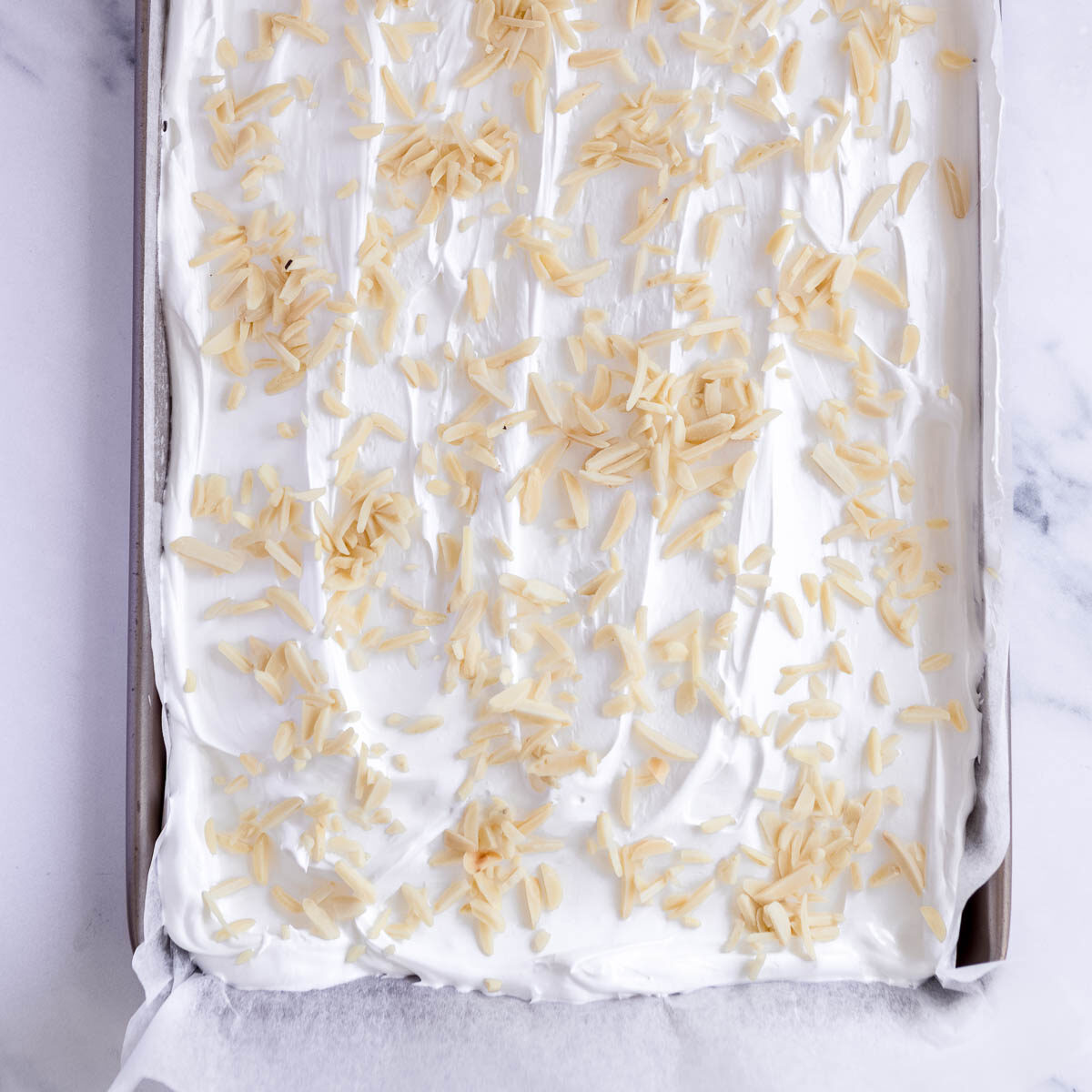 Sprinkling slivered almonds onto the meringue before baking.
