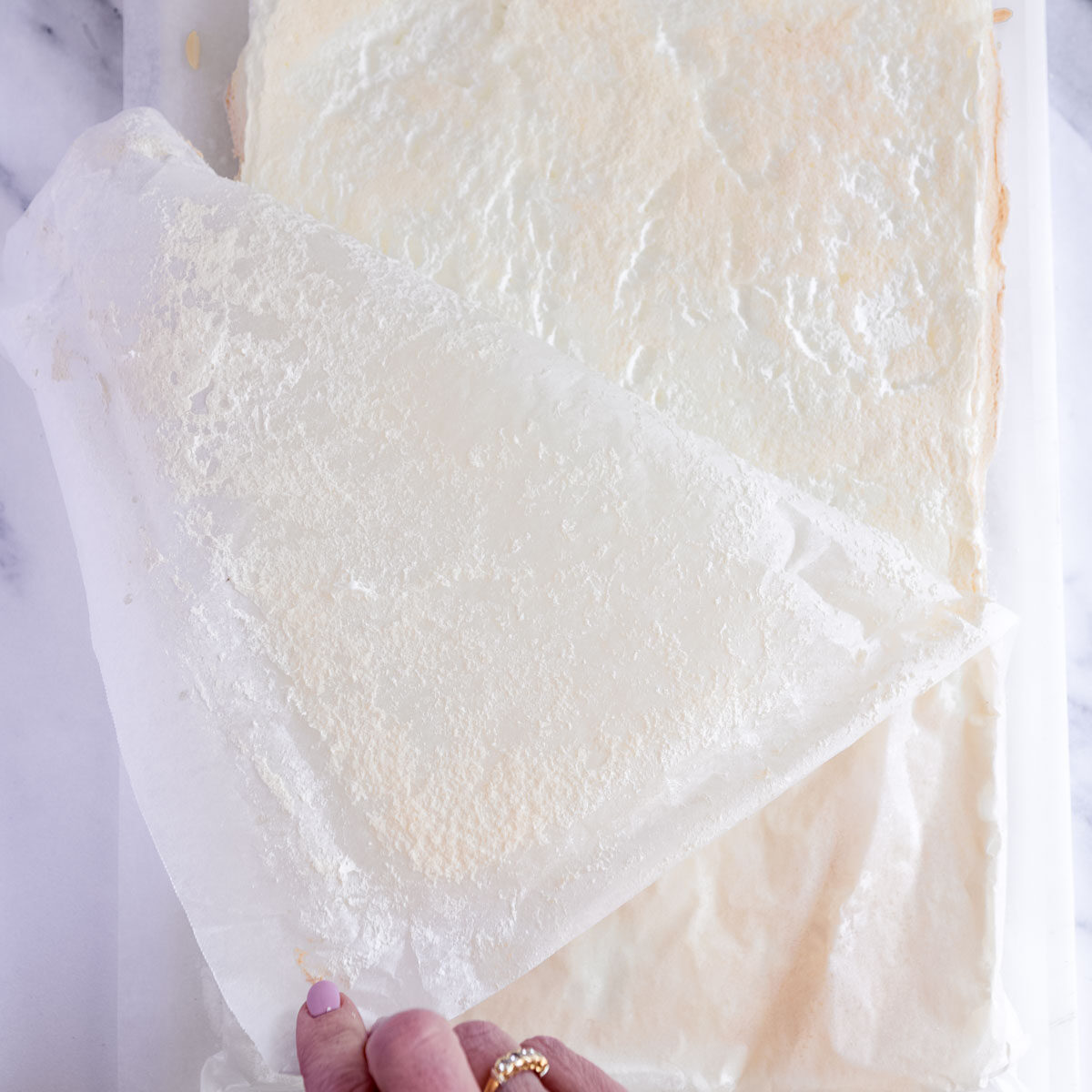 Peeling the lining paper away from the cooked pavlova.