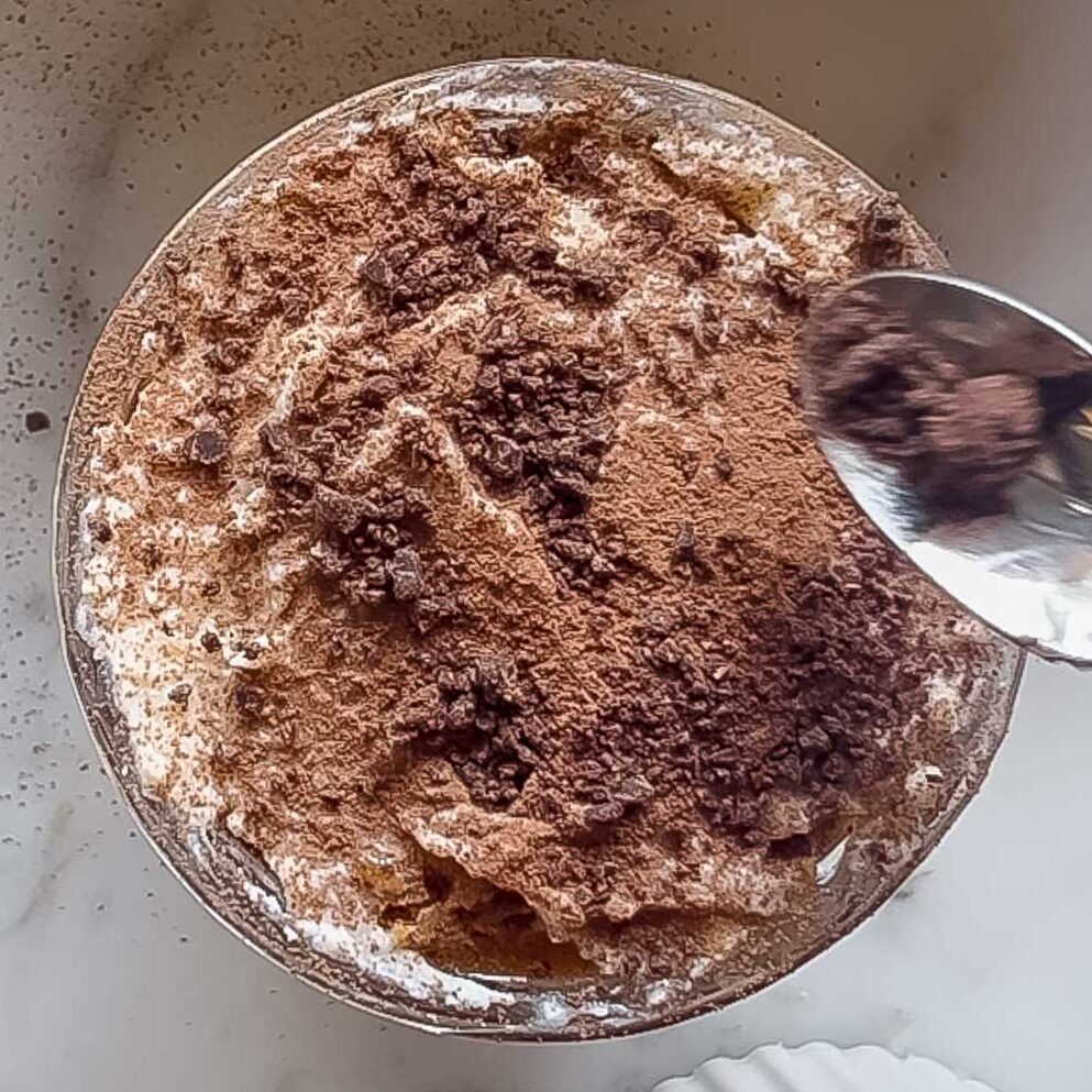 Finishing off the caramel tiramisu with a dusting of cocoa, then chopped chocolate.