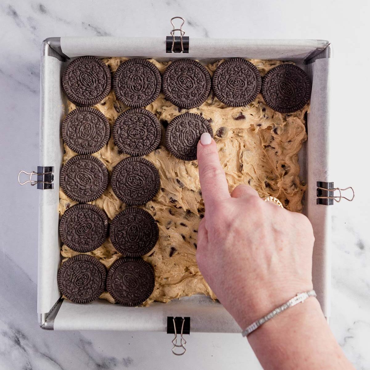 Adding a layer of Oreos, which is the second layer in these triple layer brownies.