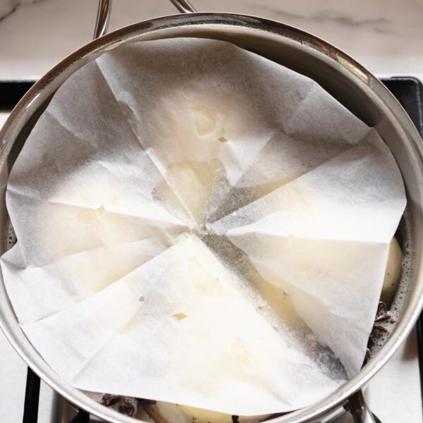 Using a disc of baking paper to keep pears submerged while poaching.