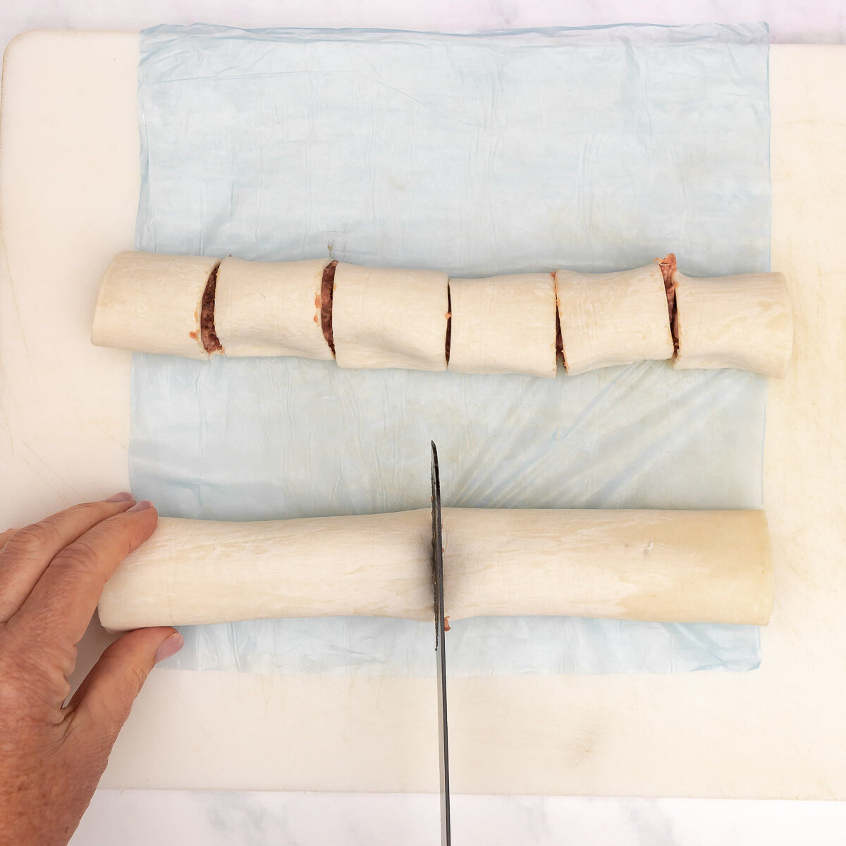 Cutting the sausage rolls into cocktail size servings.