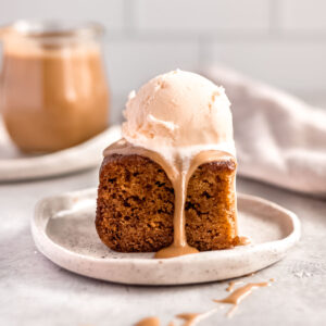 A square of sticky date pudding, topped with vanilla ice cream and rich butterscotch sauce.