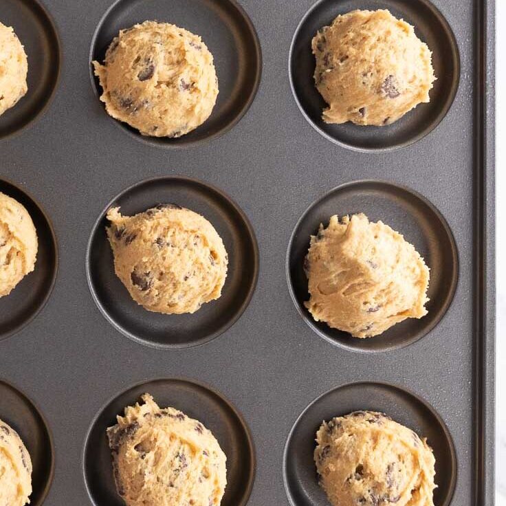 Scooping cookie dough into a muffin top pan.