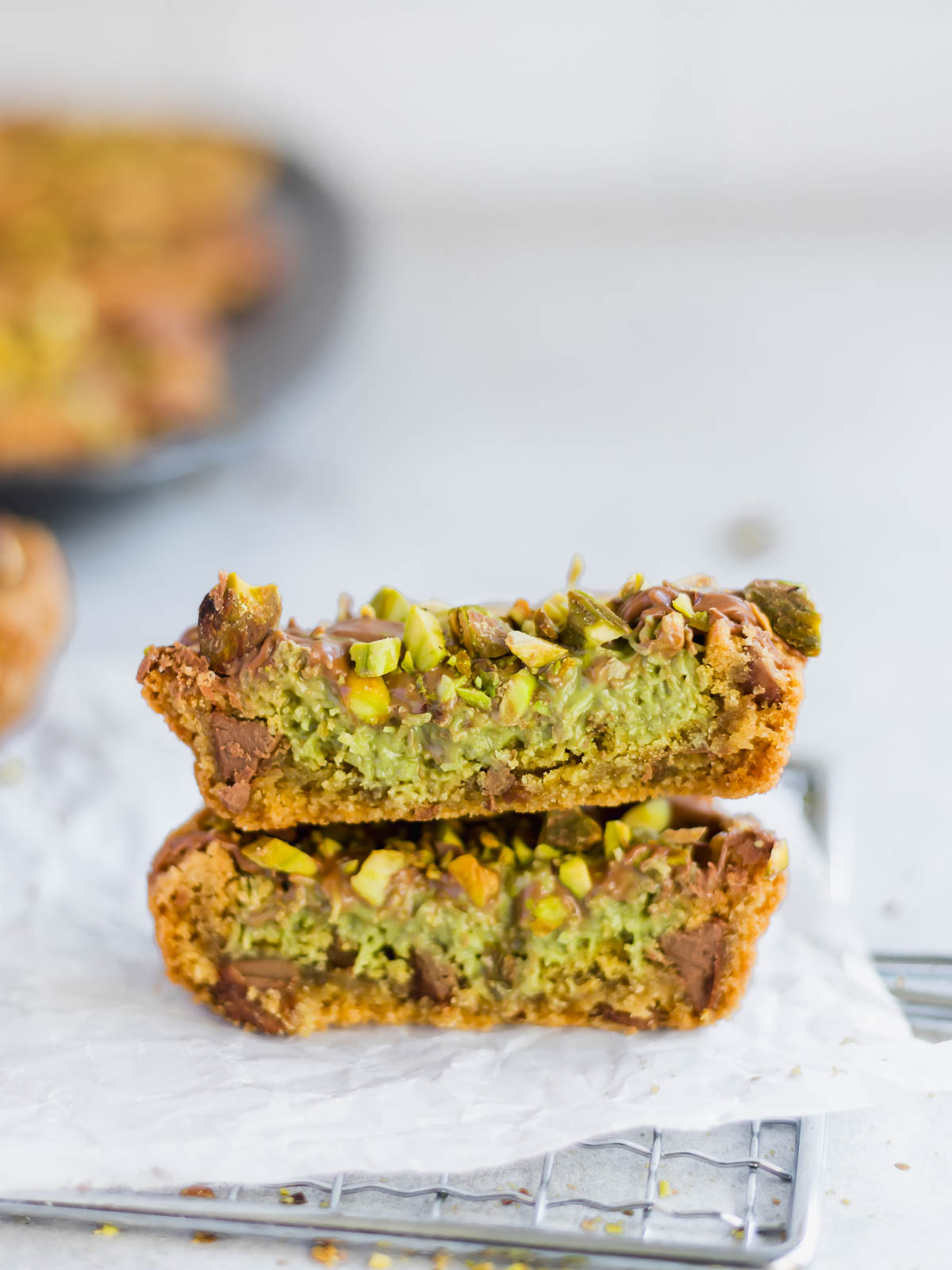 A Dubai chocolate chip cookie cut in half, to show the creamy and crunchy pistachio and toasted kataifi pastry filling.