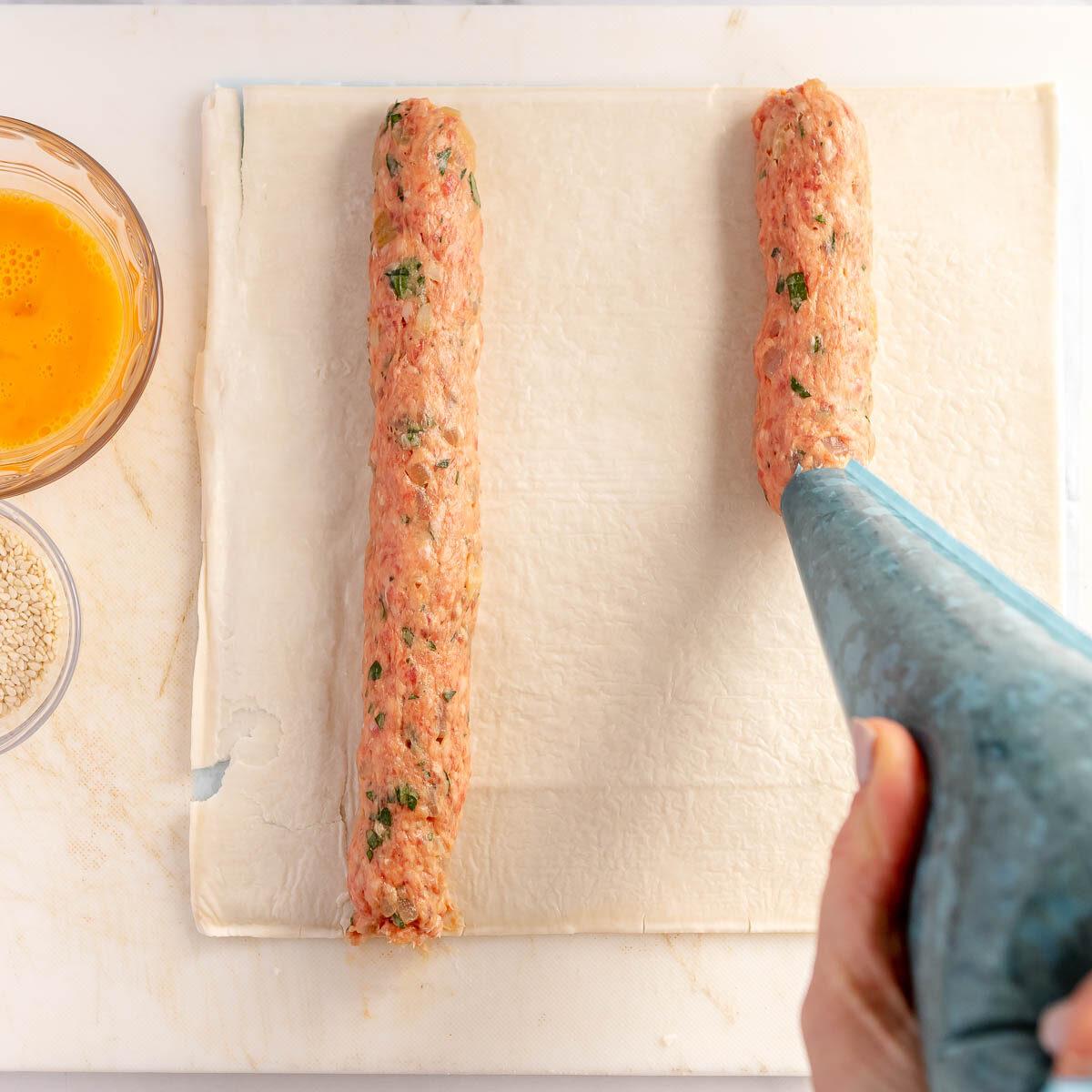 Placing the sausage roll mixture into a piping bag makes it easier to spread the mixture.