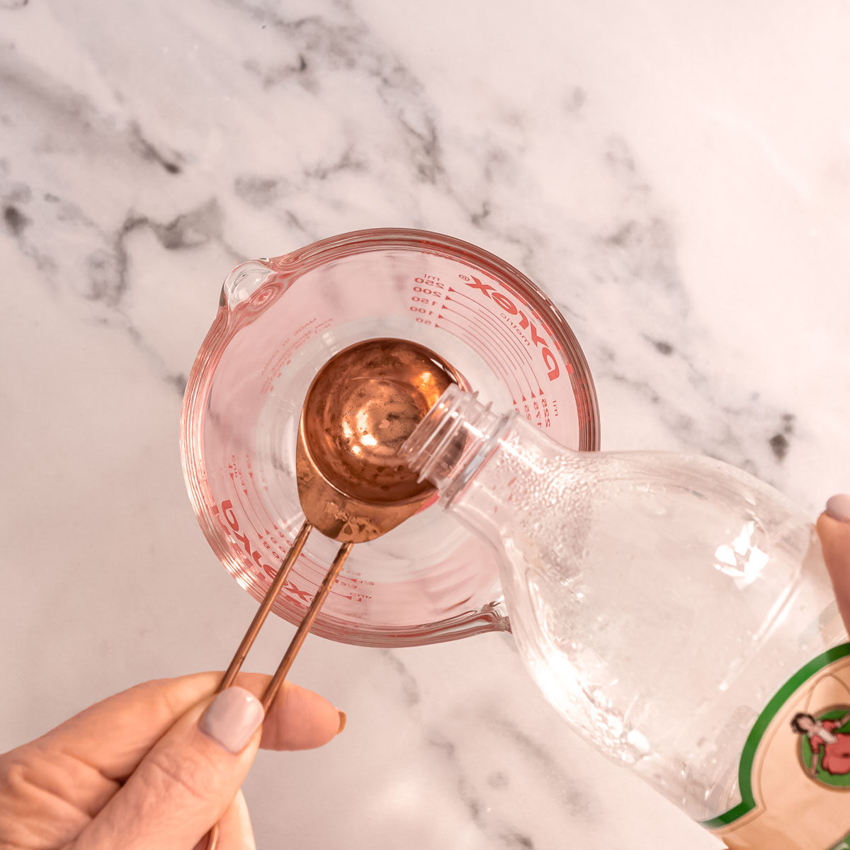 Adding 1 tablespoon of vinegar to a jug to make buttermilk.