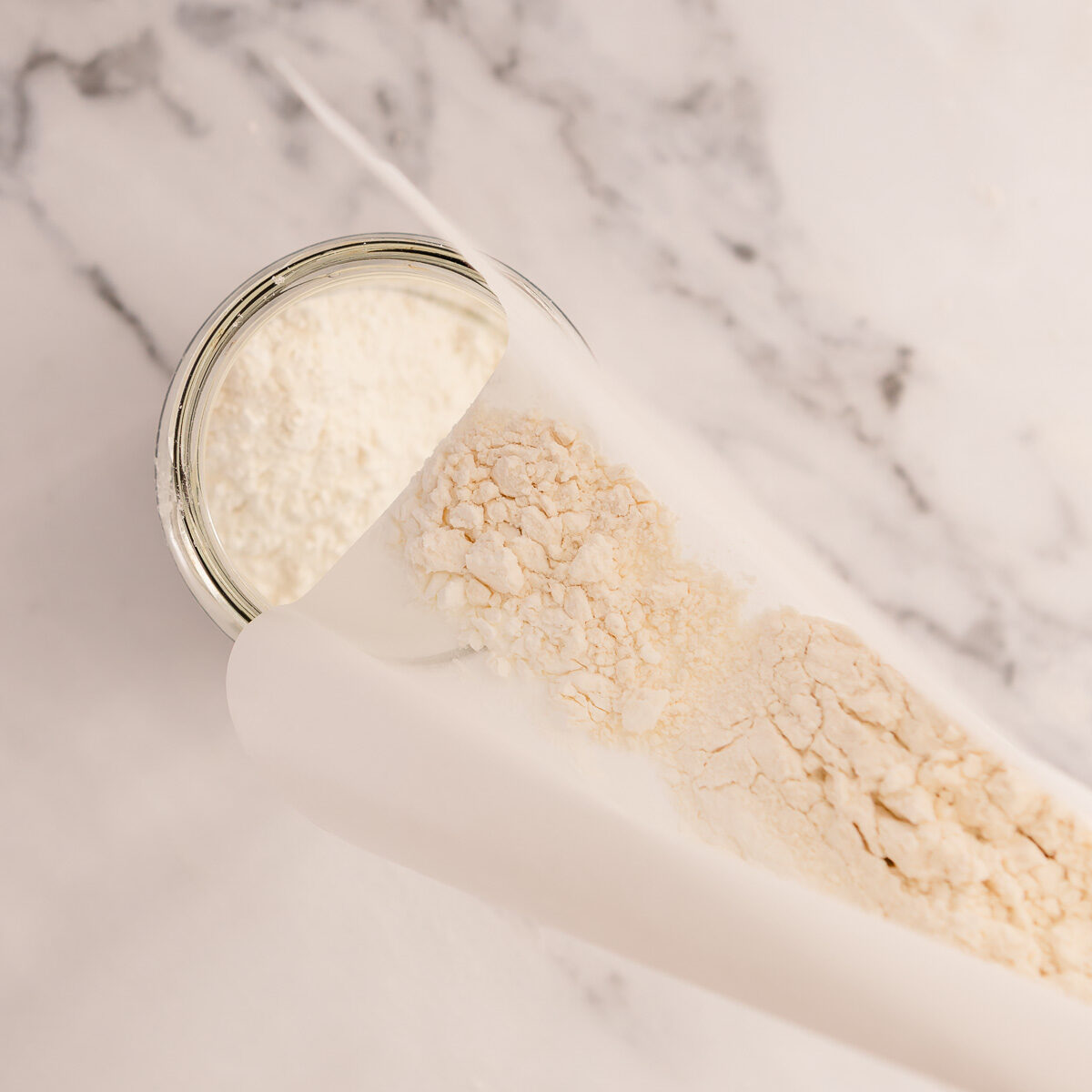 Pouring the combined flours into a jar.