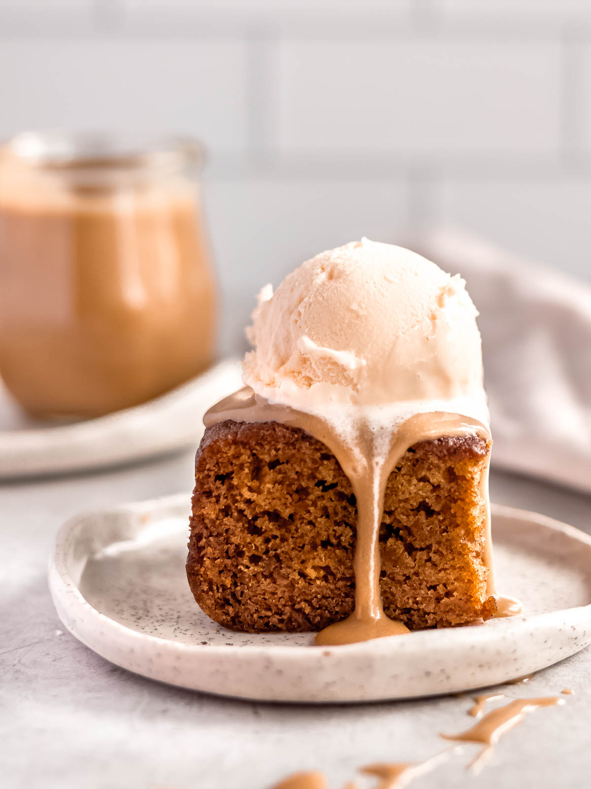 A square of sticky date pudding with ice cream and butterscotch sauce.