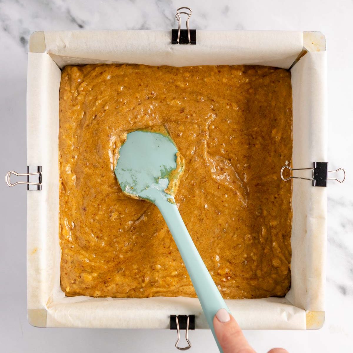 Spreading sticky date pudding mixture into prepared pan.