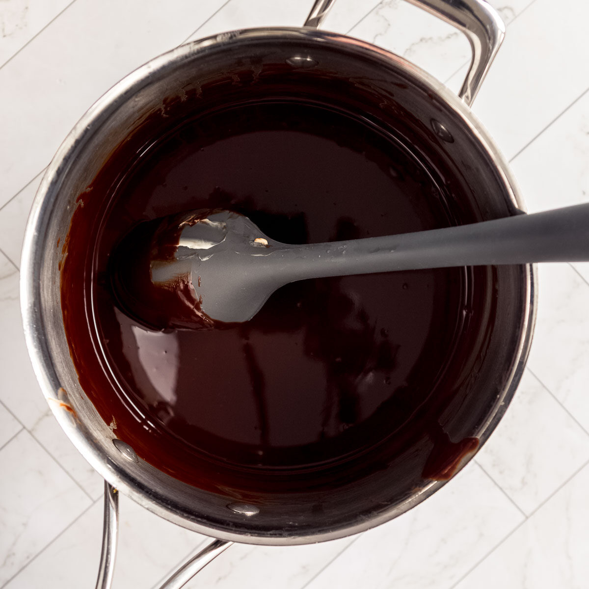 Melting chocolate and butter in a large saucepan, to make a fudgy chocolate cake for dessert.
