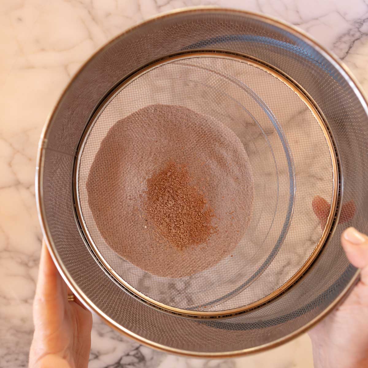 Sifting almond meal, cocoa powder and icing sugar, as the dry ingredients.