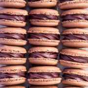 Rows of chocolate macarons, filled with chocolate ganache.