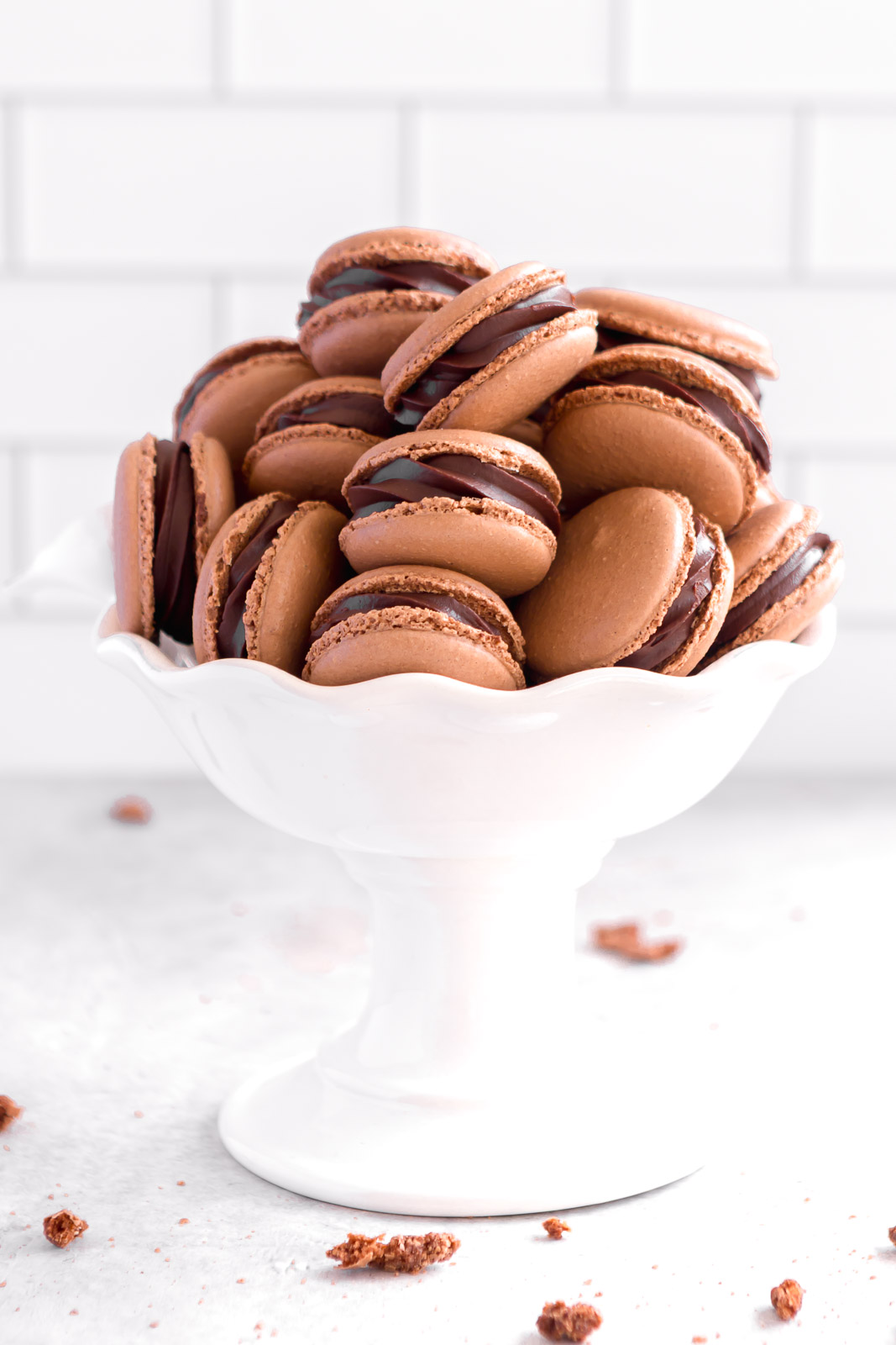 A white bowl filled with beautiful homemade chocolate macarons.