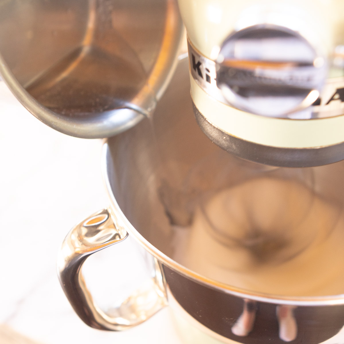 Adding sugar syrup to whipped egg whites.