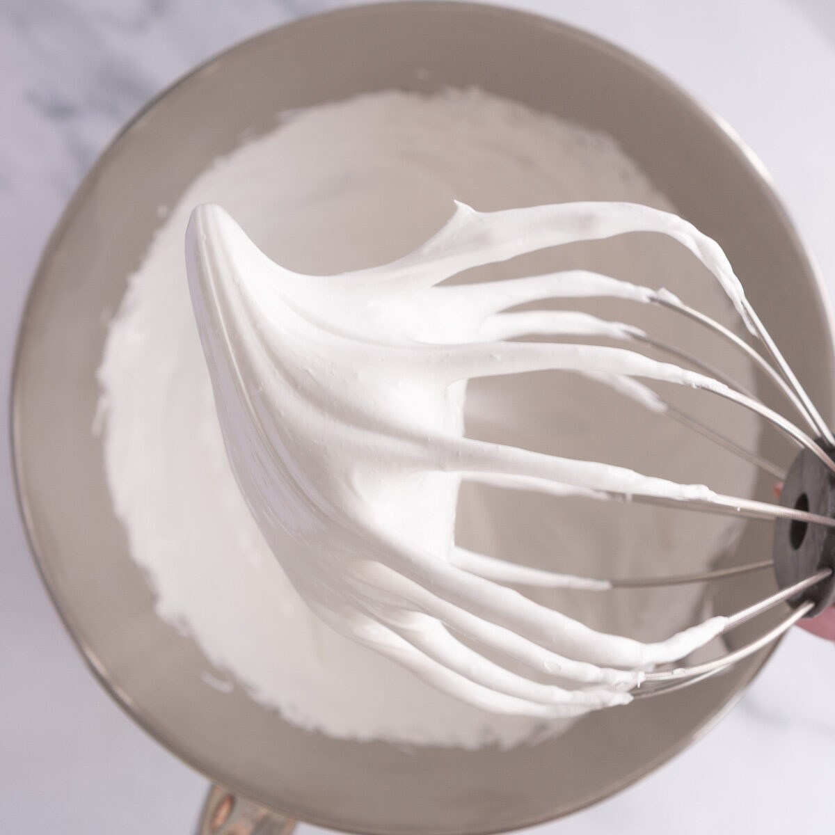 Whisking the egg whites and caster sugar into a glossy meringue.
