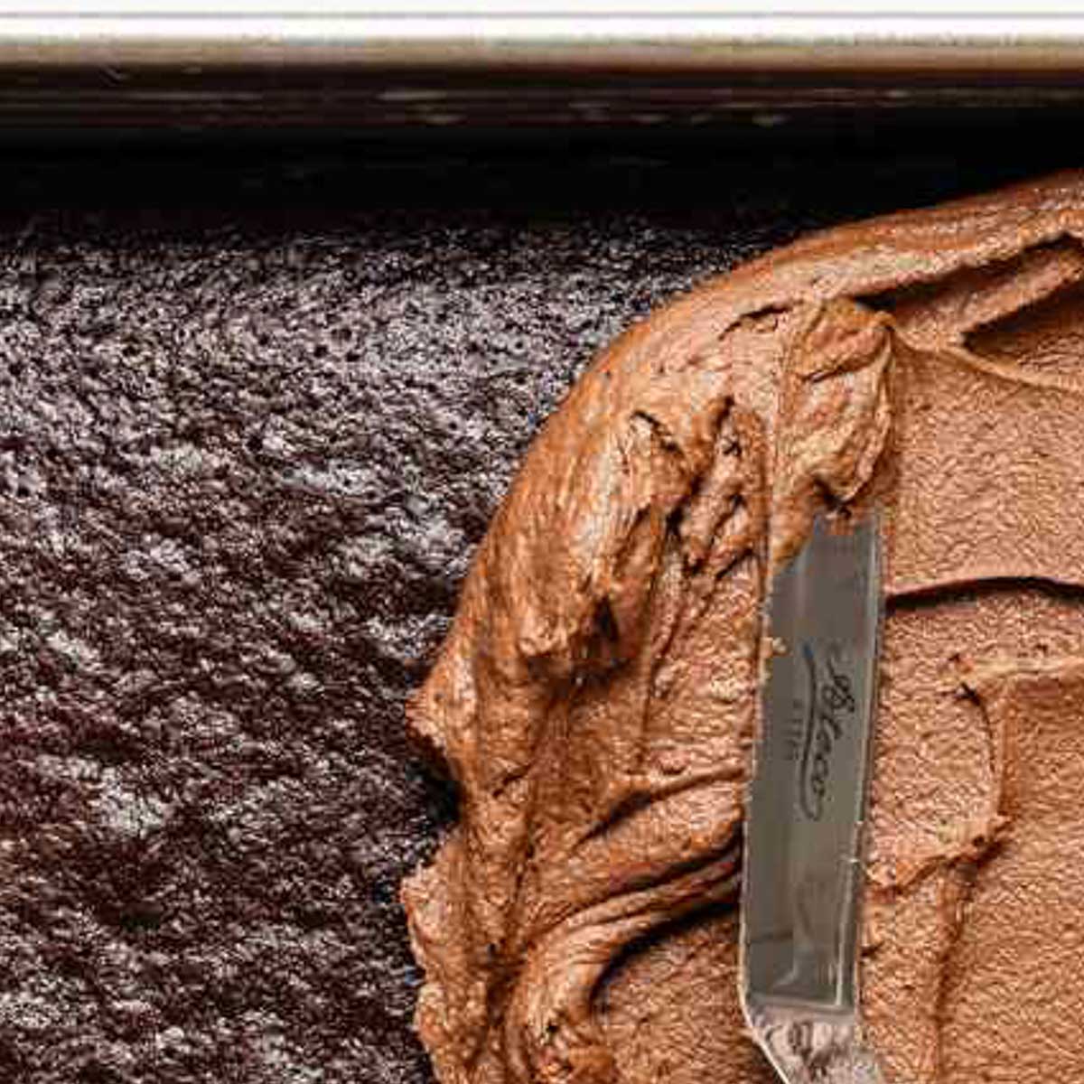 Spreading fudgy chocolate frosting onto a chocolate cake.