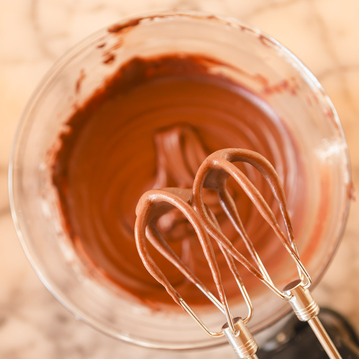 Beating ingredients together to make a thick, fudgy chocolate frosting.