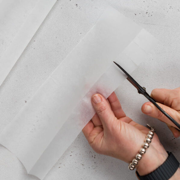 Using scissors to cut tabs into the strips of baking paper.