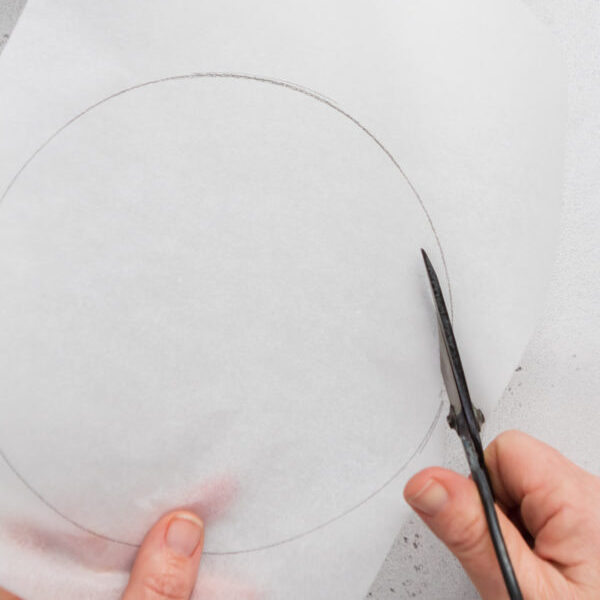 Cutting a circle inside of outline of a round cake tin.