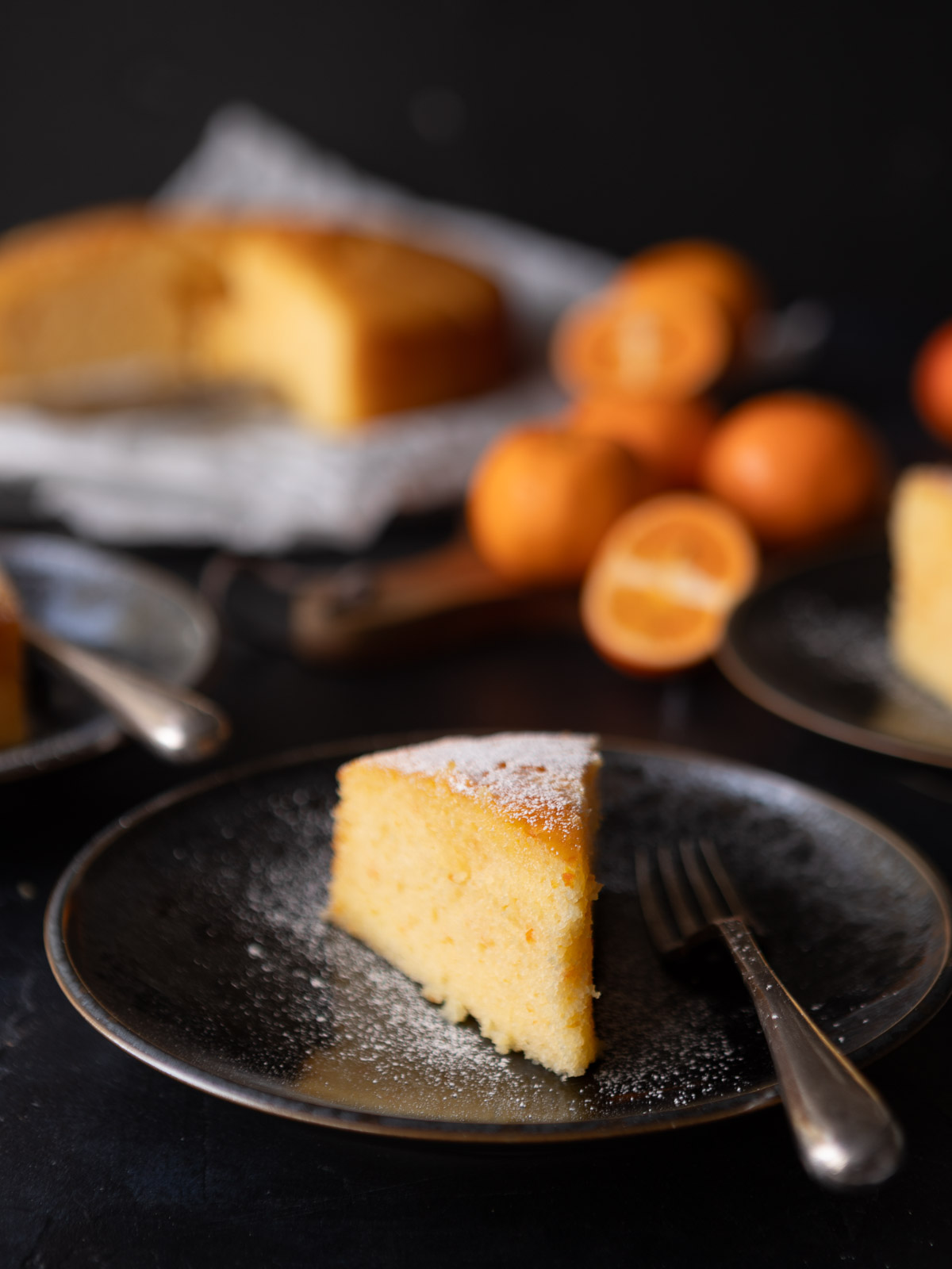 A wedge of moist mandarin almond cake, dusted with icing sugar.