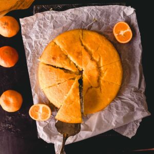 A round mandarin cake made with almond meal and yogurt, cut into wedges.