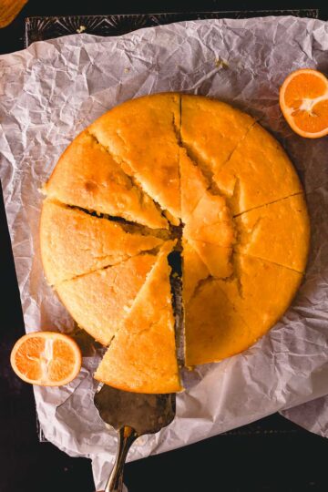 A round mandarin cake made with almond meal and yogurt, cut into wedges.