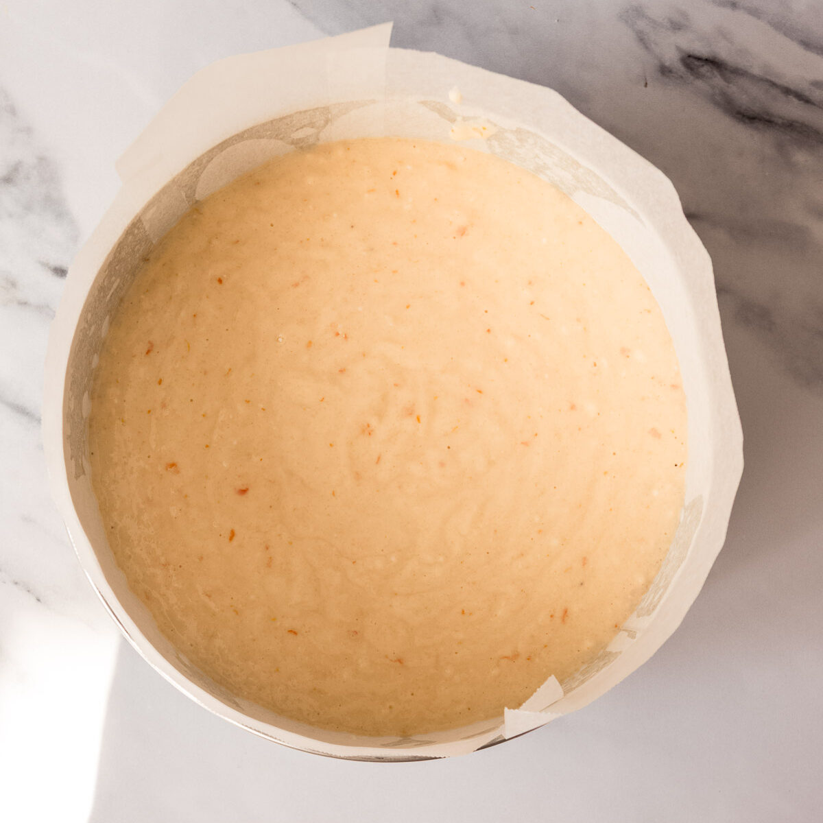 Cake batter in a round cake tin, ready to be baked.