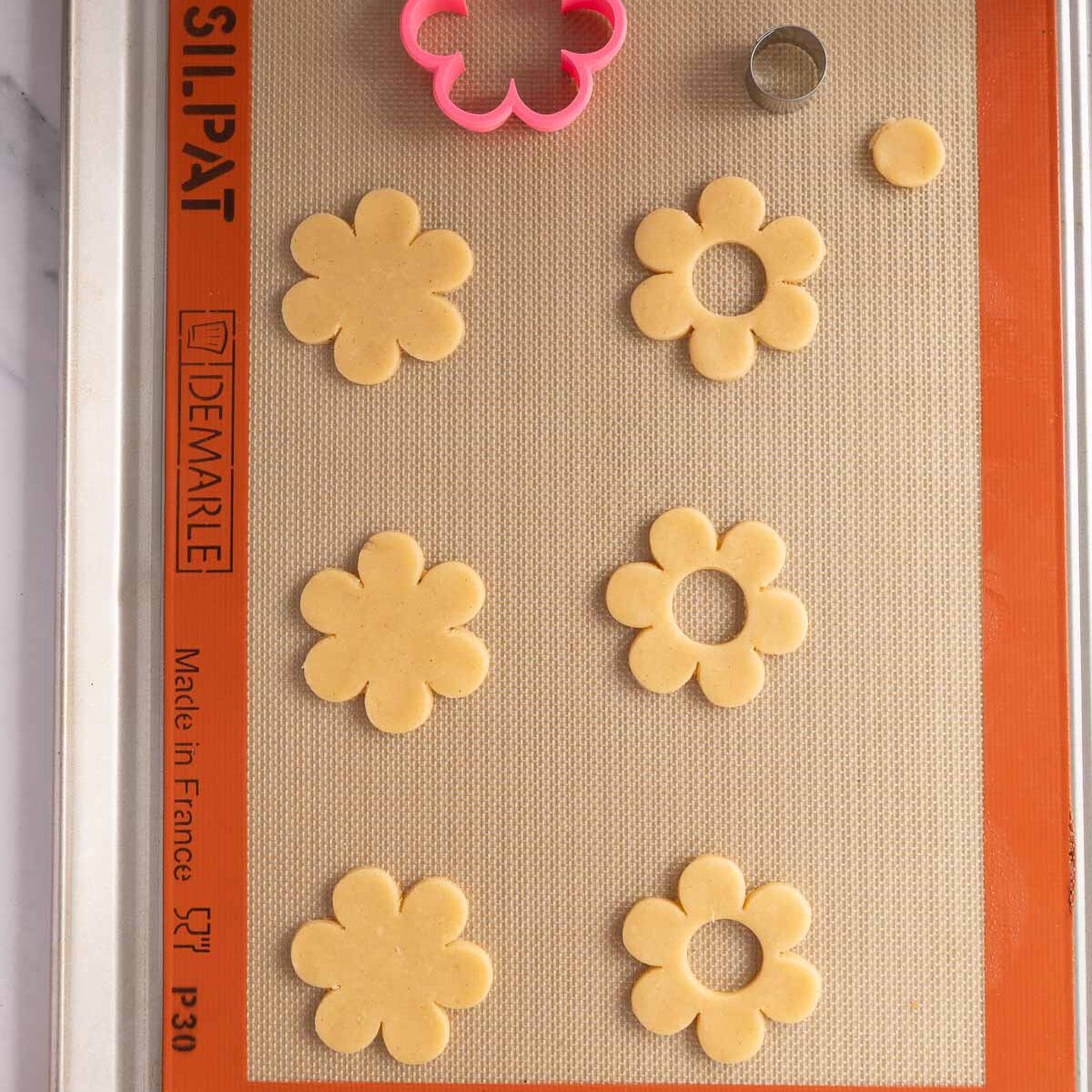 Cut out small holes in the centre of half of the cookies.