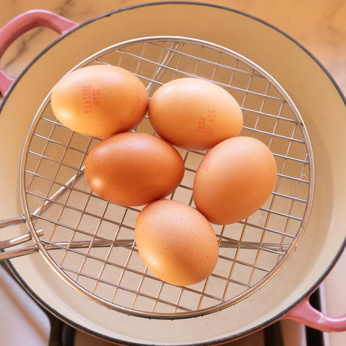Carefully placing eggs into boiling water, to make the perfect boiled eggs for curried devilled eggs.